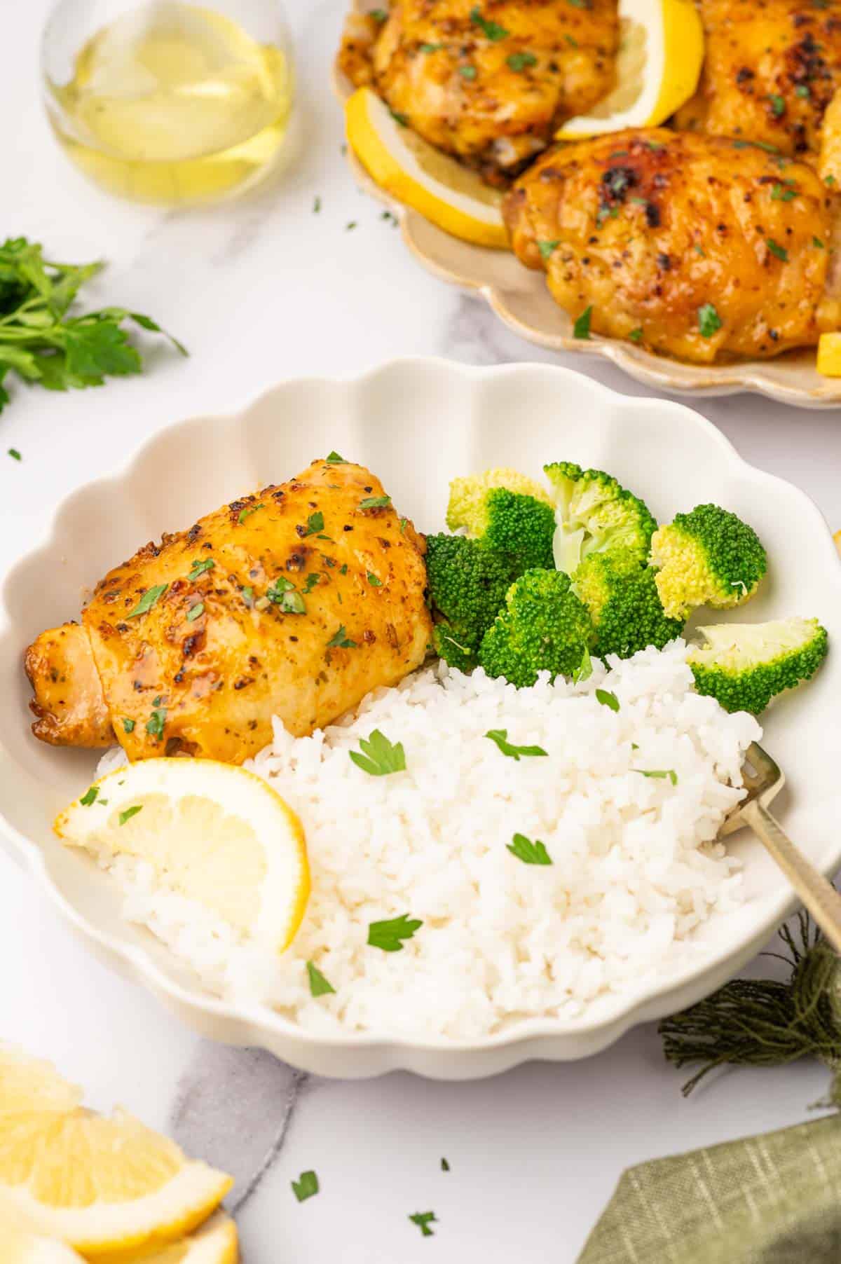 Baked lemon pepper chicken thighs served with rice and broccoli