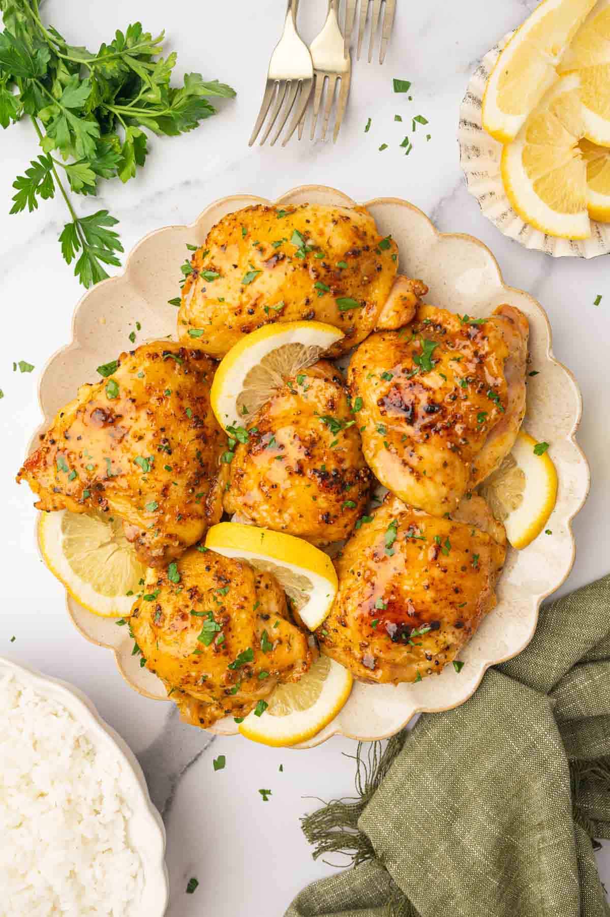 oven baked chicken thighs plated in decorative plate with lemon wedges on the side