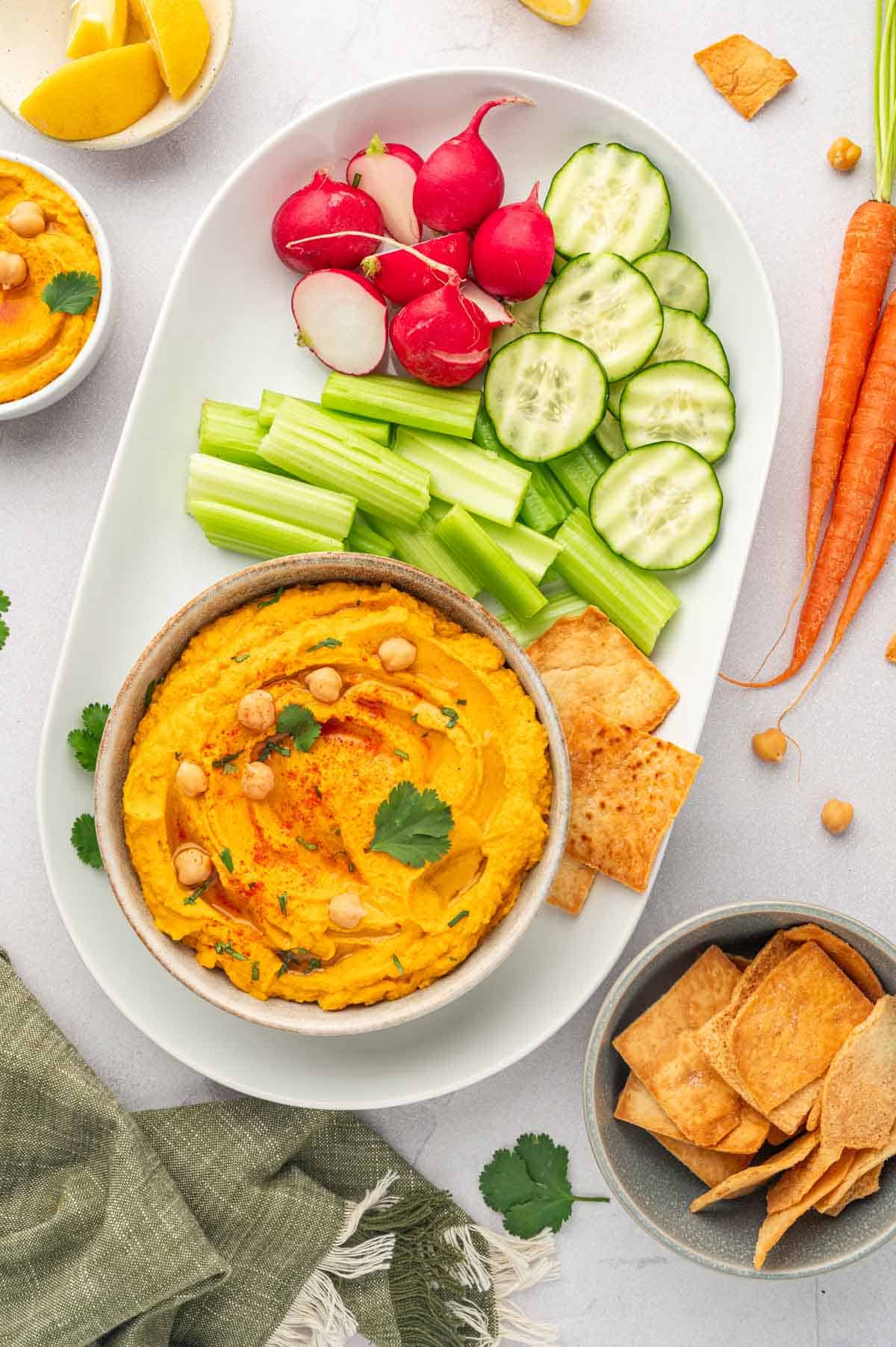 Roasted carrot hummus with canned chickpeas- served in a platter with veggies and pita chips