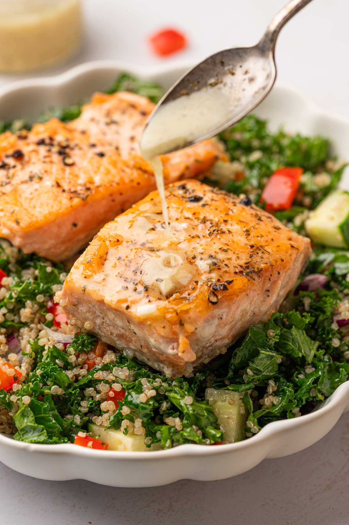 Lemon Dijon dressing drizzle on a salmon kale quinoa salad