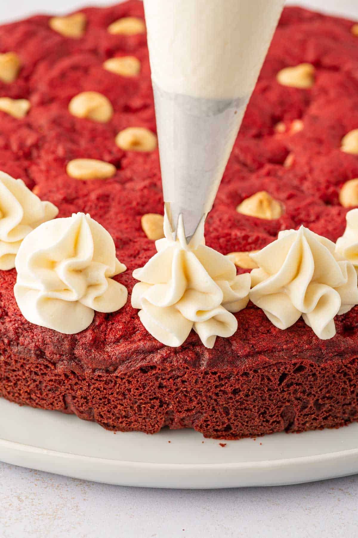 Piping the frosting on a valentines cookie cake