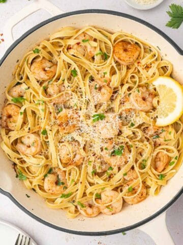 Easy shrimp scampi fettuccine in a white skillet and garnished with parsley