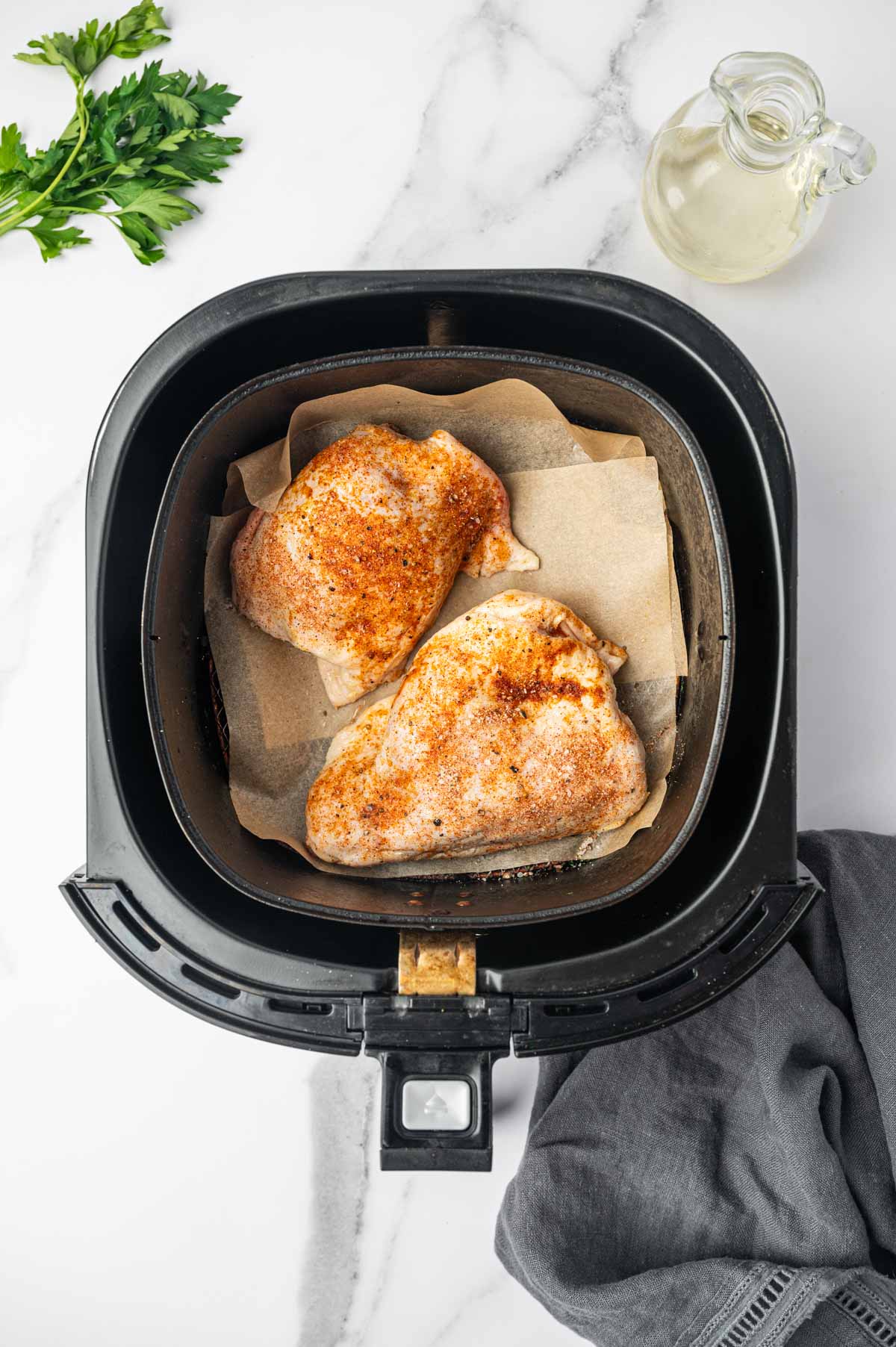 Seasoned chicken thighs placed in the air fryer