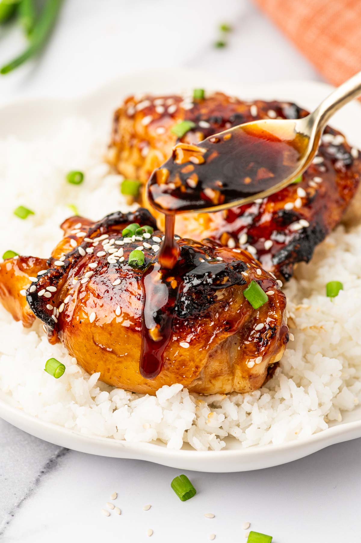 Close-Up of Air Fryer Teriyaki Chicken Thighs Garnished with Sesame Seeds with teriyaki sauce drizzle.