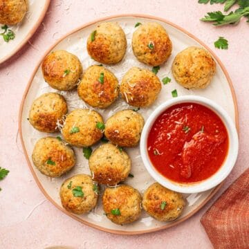 Juicy Chicken Meatballs in a white plate with marinara sauce on the sides.