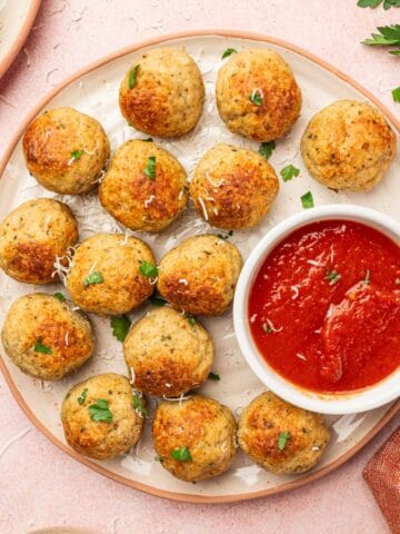 Juicy Chicken Meatballs in a white plate with marinara sauce on the sides.