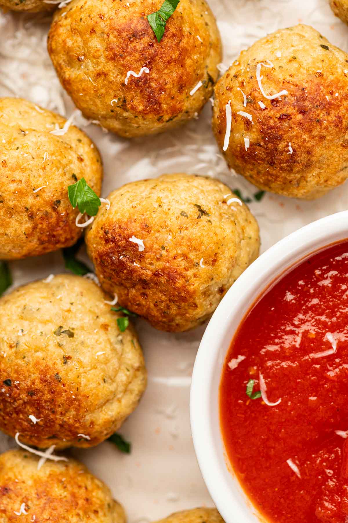 CLose up shot of chicken Meatballs near marinara sauce.