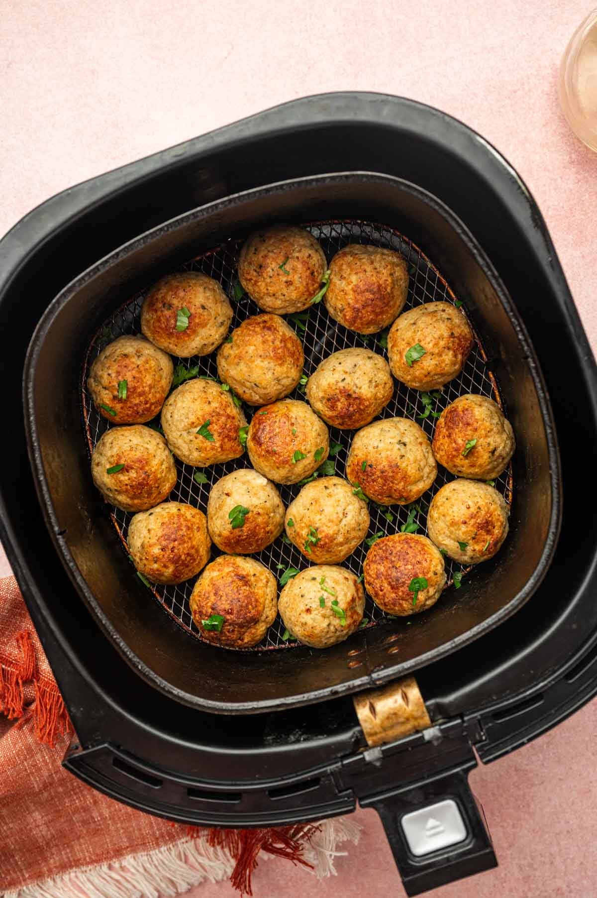 Air Fryer Chicken Meatballs with Parmesan in an air fryer basket. 