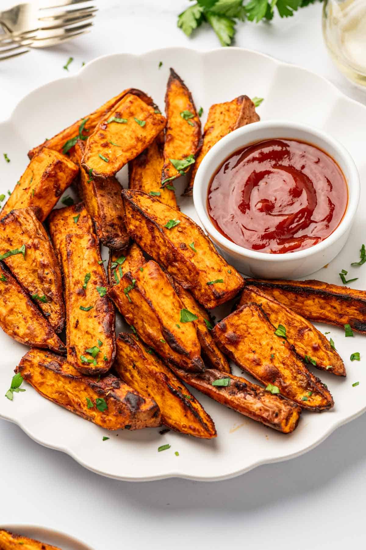 Easy air fryer recipe for sweet potato wedges with spices, served warm on a white marble table.