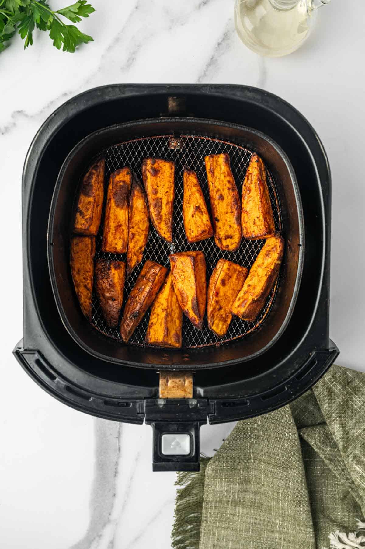 Golden brown sweet potato wedges seasoned with paprika and garlic powder, freshly cooked in an air fryer.