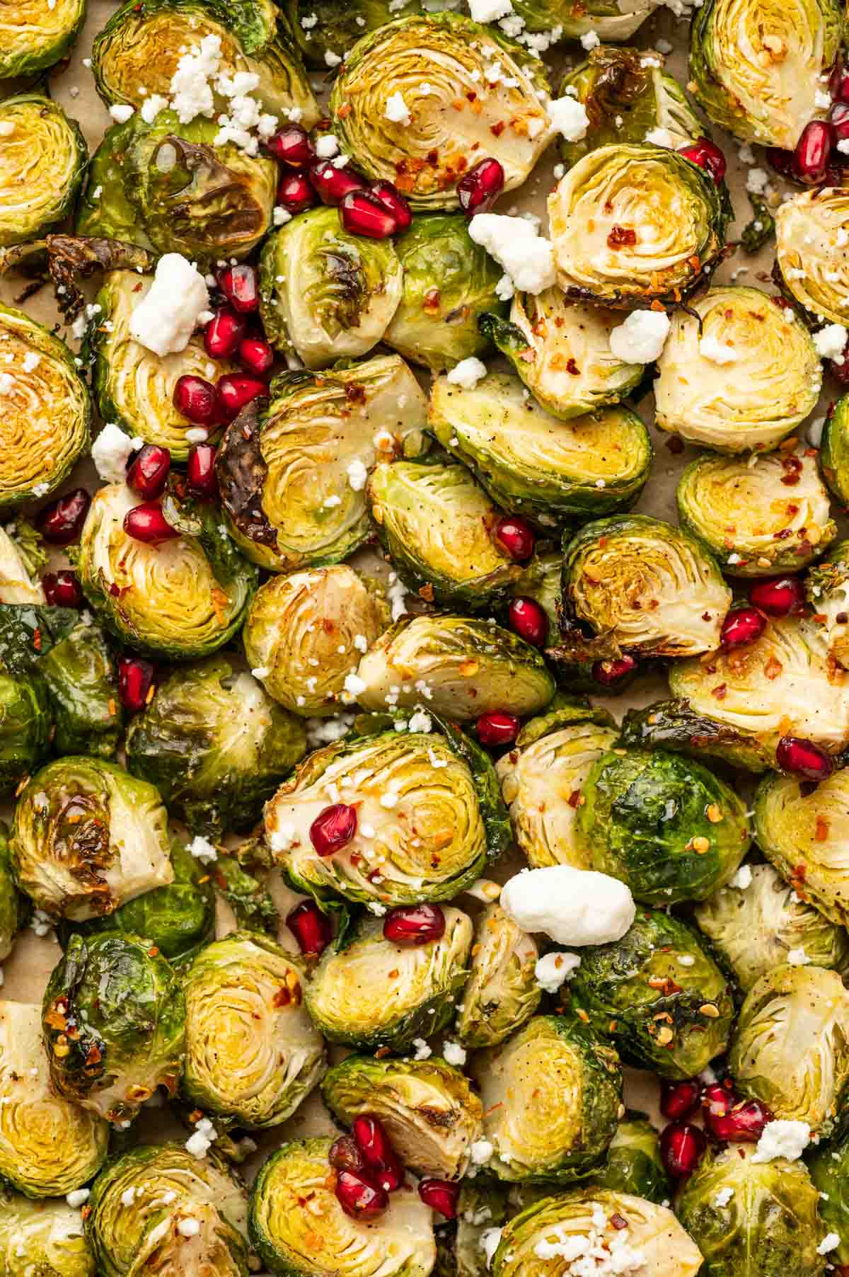 Hot honey Brussels sprouts garnished with pomegranate seeds and goat cheese