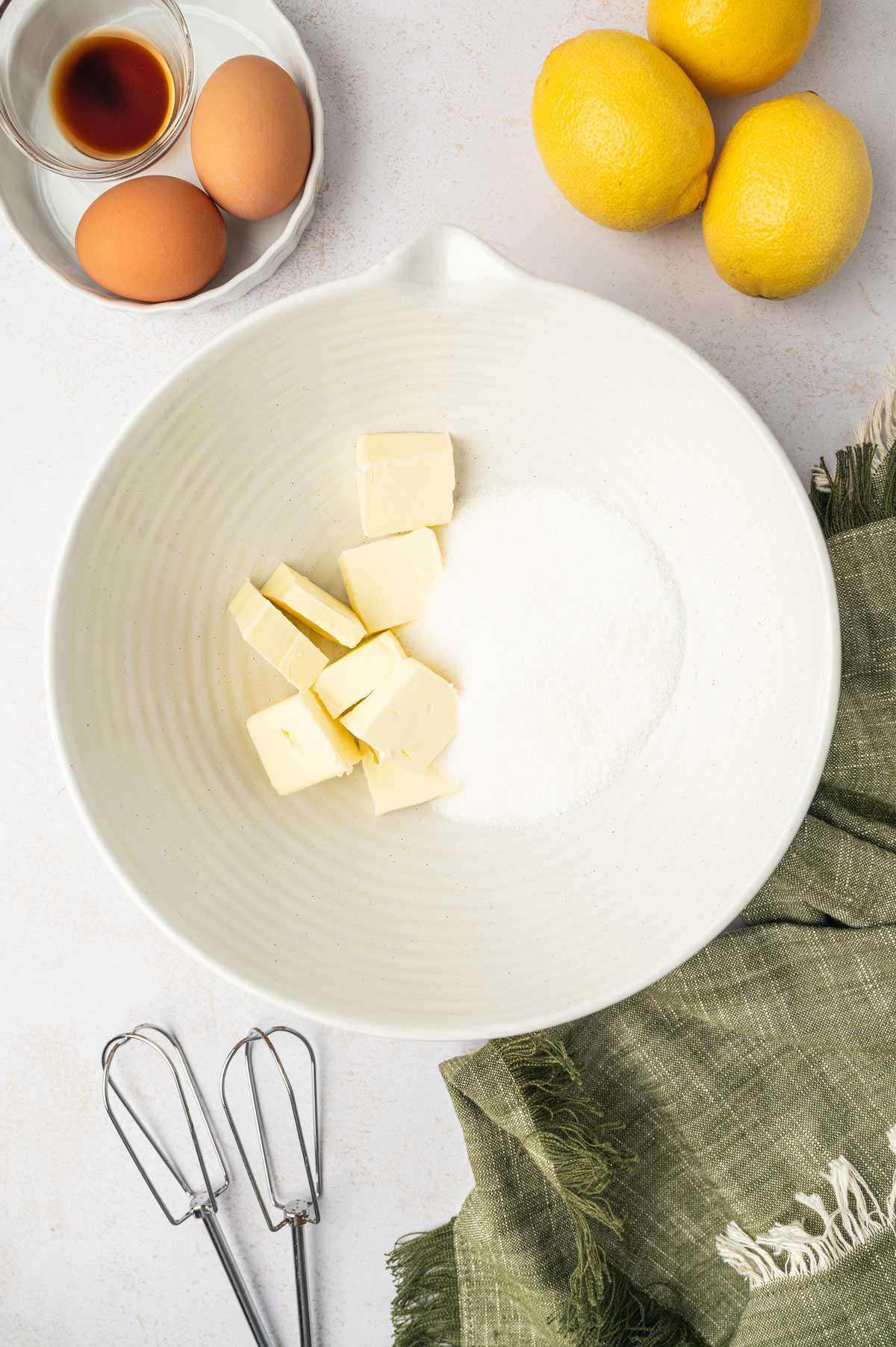 In a white bowl butter and sugar for mini lemon mini bundt cakes.