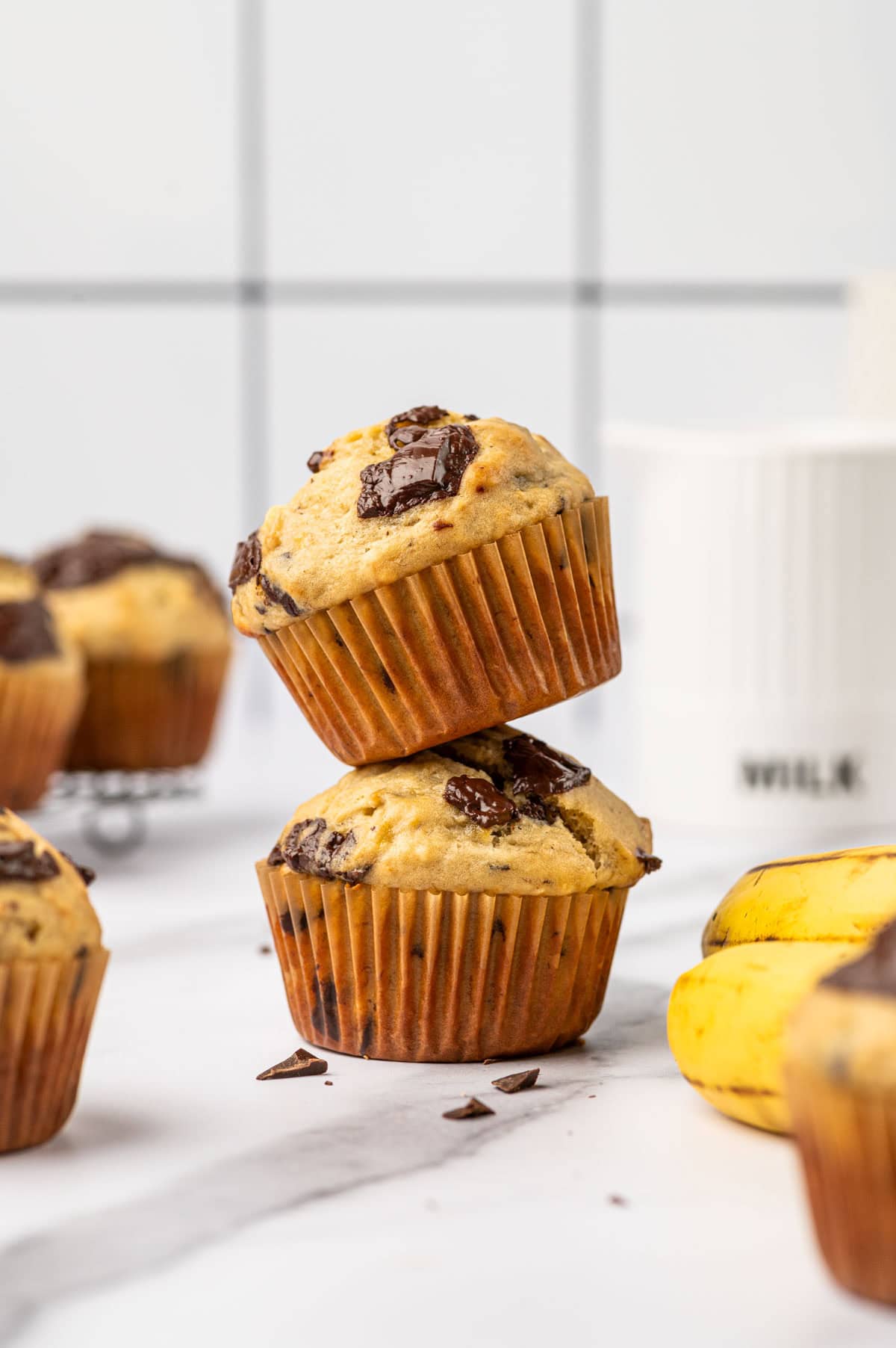 Stack of banana chocolate chunks muffins one above the other in a marble surface.