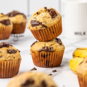 Banana chocolate chunk muffins stacked one above the other.