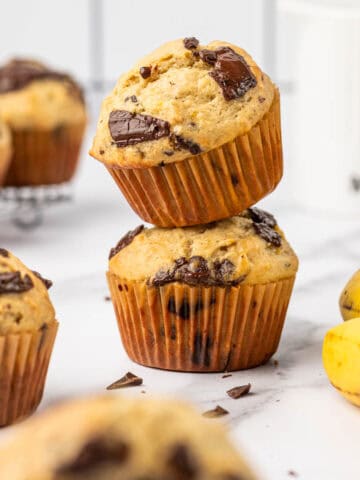 Banana chocolate chunk muffins stacked one above the other.