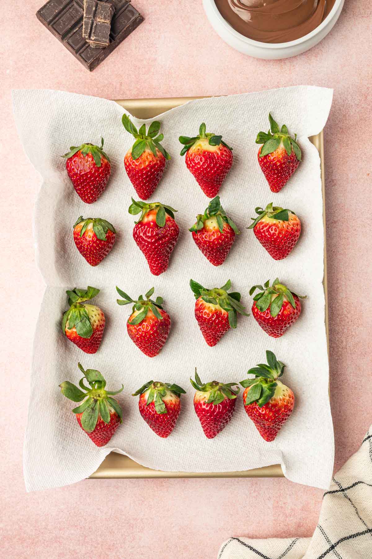 Drying the fresh strawberries in a baking tray lined with parchment paper.