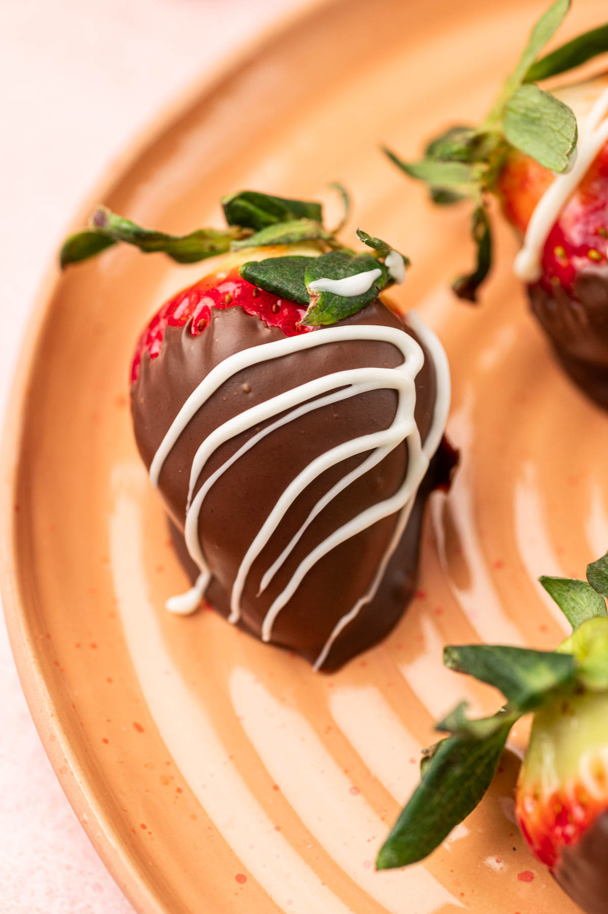 Single nutella covered Strawberry n a orange plate.