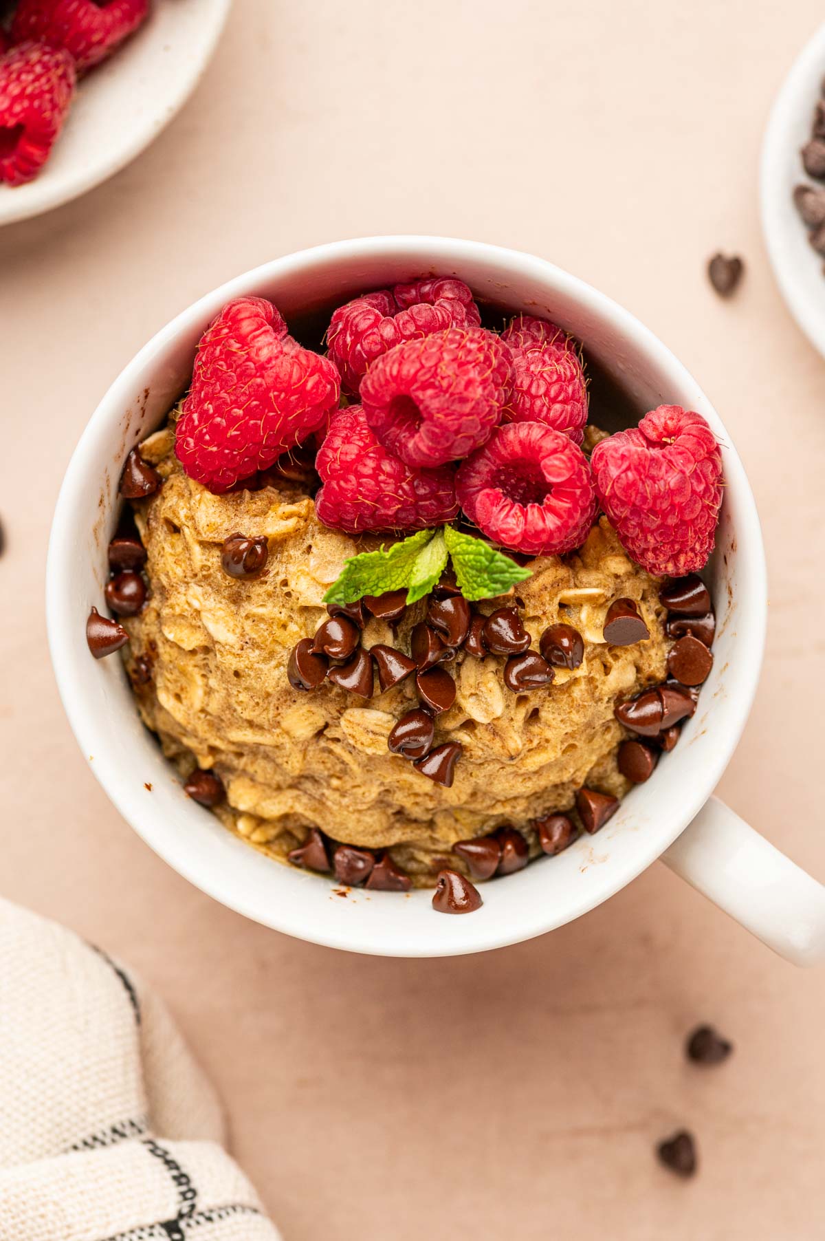 Top angle of oatmeal mug cake topped with raspberries and chocolare chips.