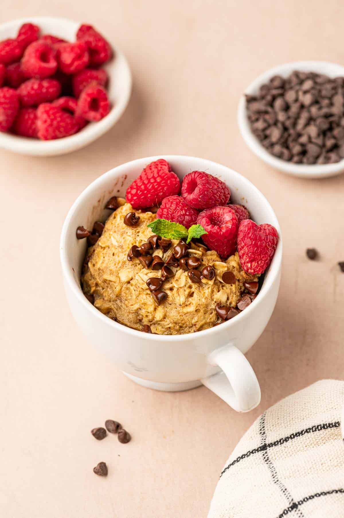 Oatmeal mug cake with raspoberries and chocolate chips in the sides.