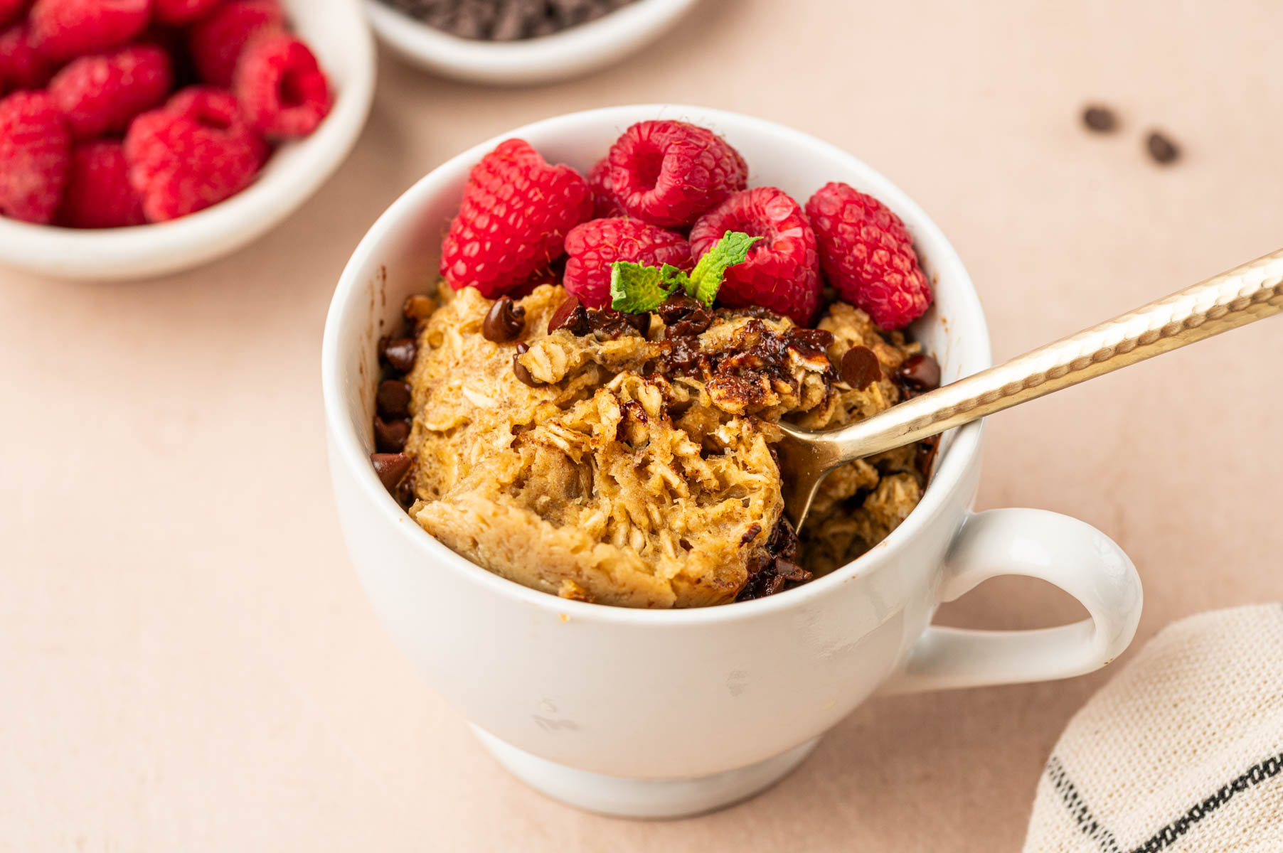 Horizontal image of oatmeal mug cake with spoon getting scooped.