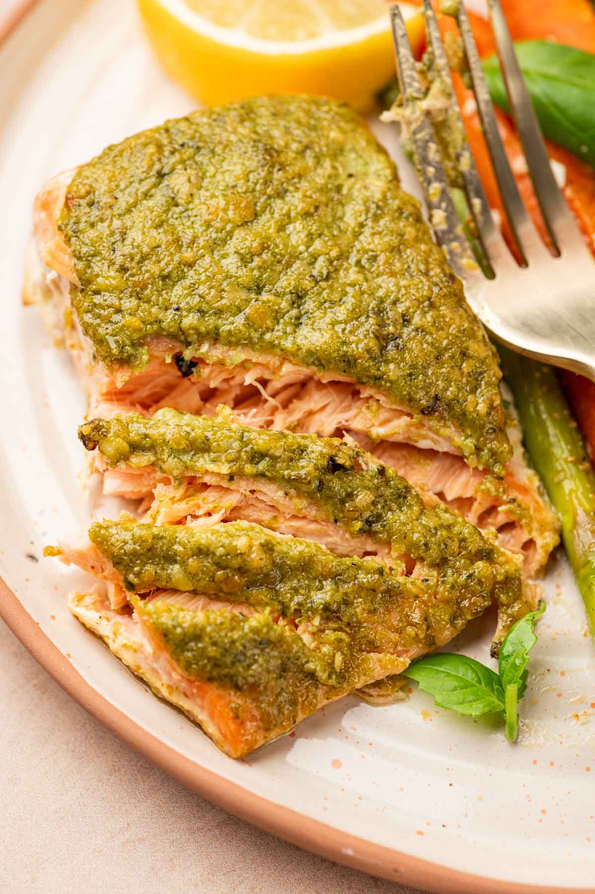 Flaky pesto butter salmon in a serving plate with a fork.