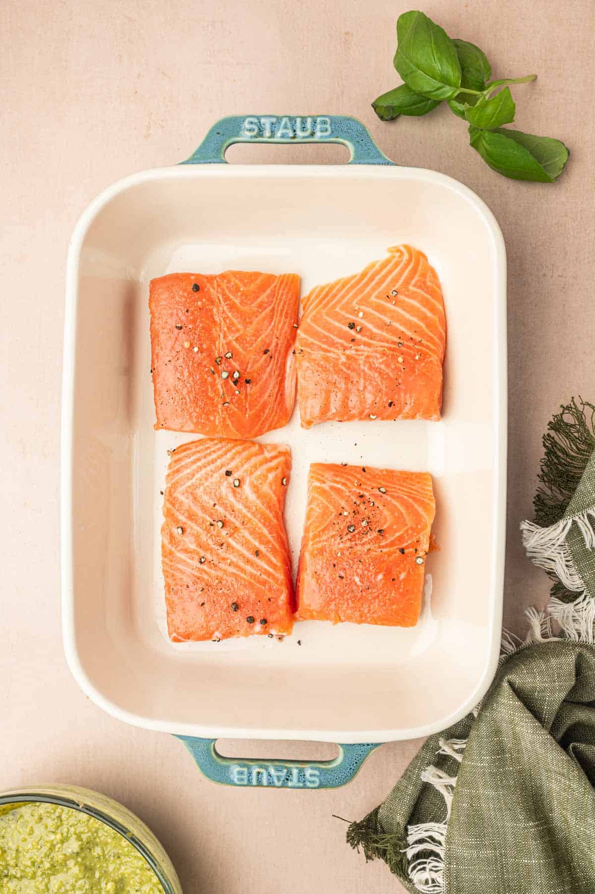 Seasoned salmon filets with salt and pepper in a baking dish.