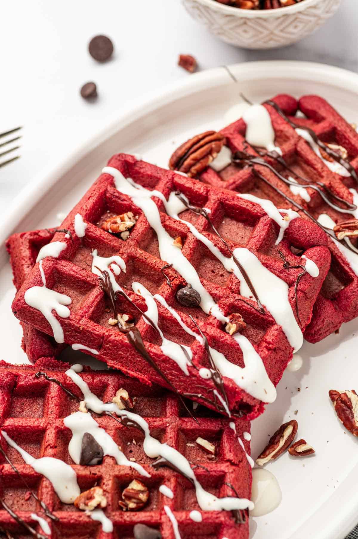 Backlit shot of red velvet waffles, drizzled chocolate ganache and cream cheese drizzle.