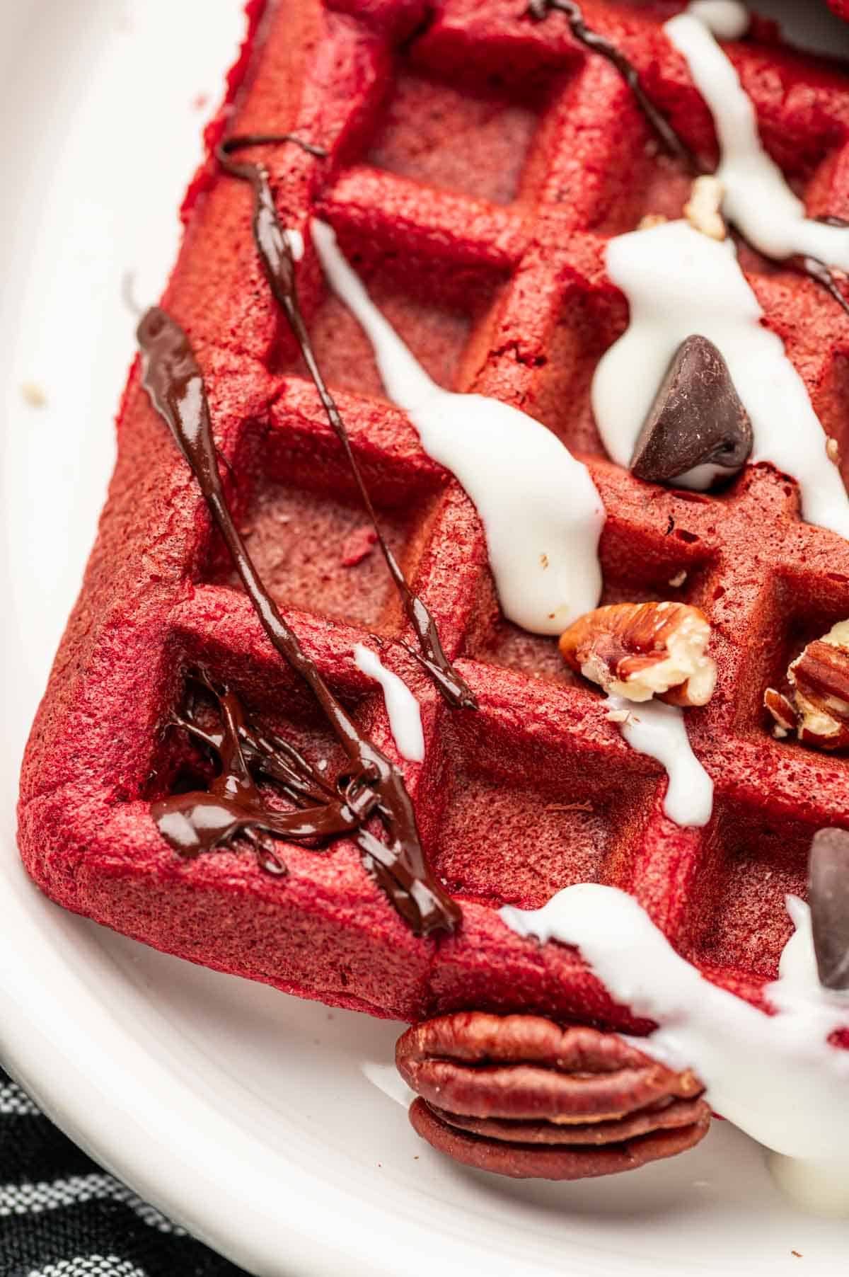 Cream cheese and chocolate ganache drizzled  over the red velvet waffles and topped with pecans.