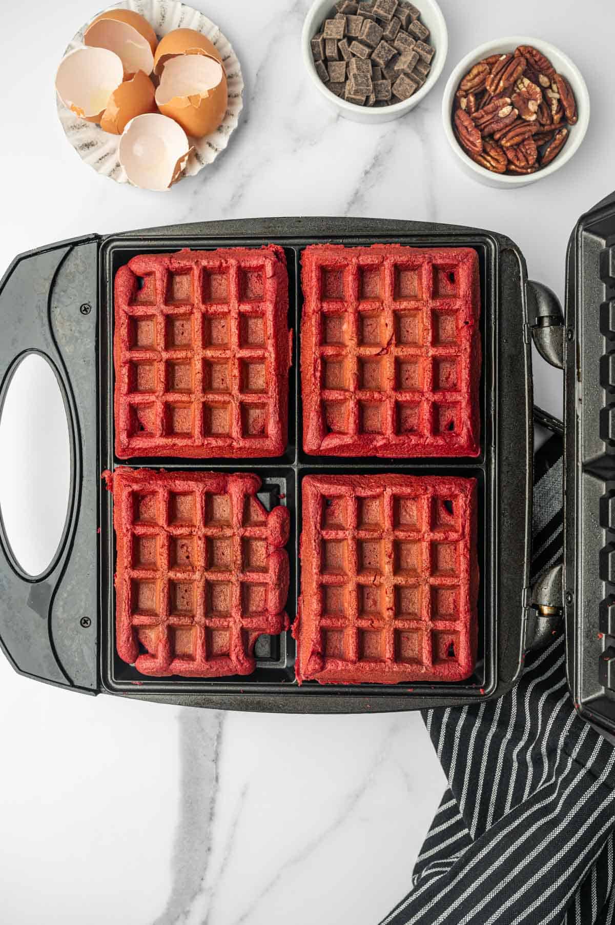 Red velvet cake waffles cooked in a waffle maker.