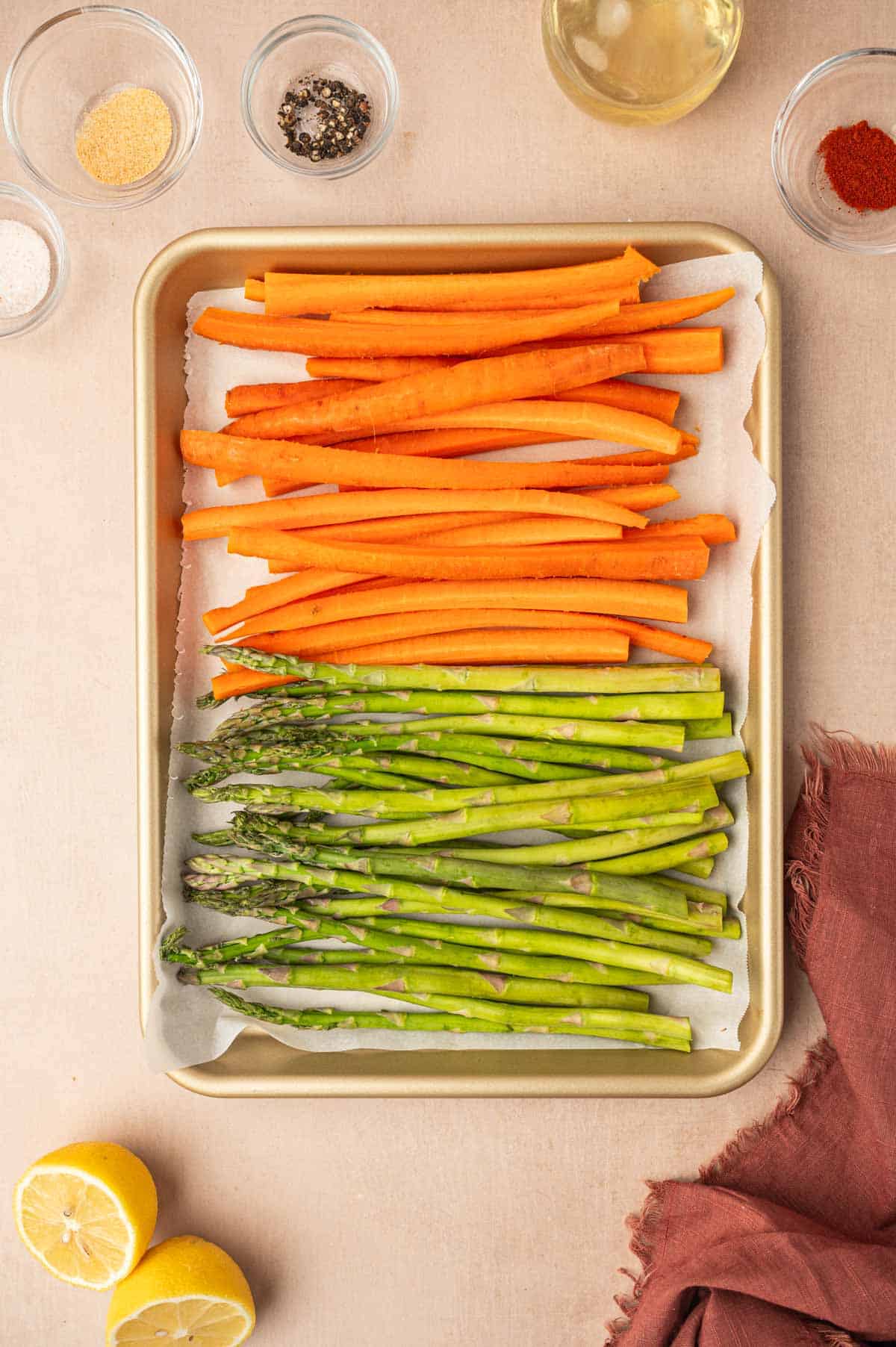 The carrots and asparagus cut into equal length and arranged on a baking sheet.