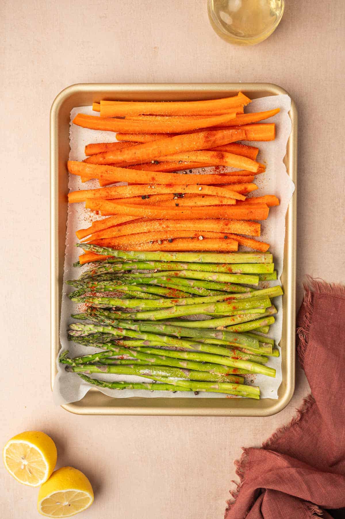 The seasonings added to the carrots and asparagus recipe in a baking sheet.