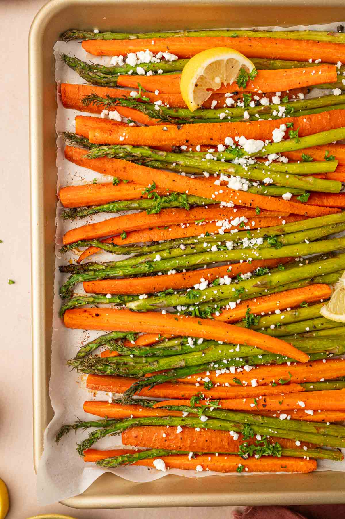 Roasted carrots and asparagus resting after out from the oven. Garnished with goat cheese and parsley.