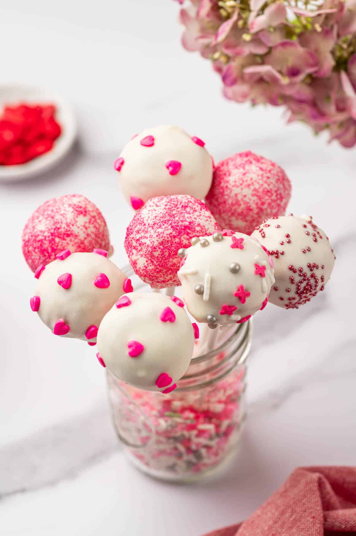 Backlit shot of valentine cake pops with red heart sprinkles in the side.