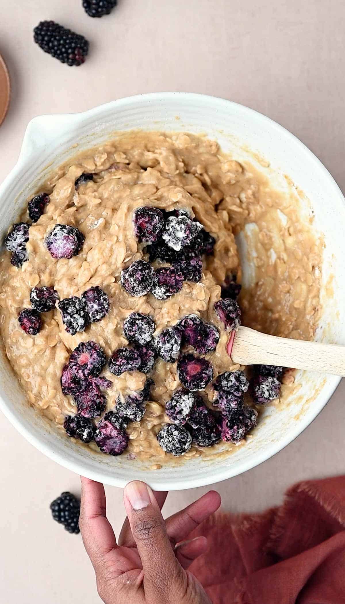 The flour coated blackberries are added to the muffin batter for making Banana Blackberry Oatmeal Muffins.