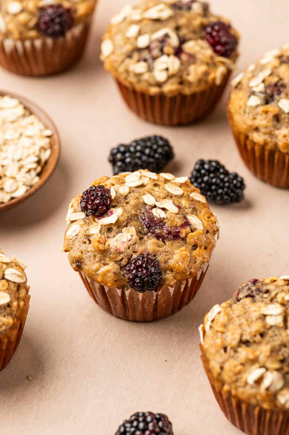 Group of banana blackberry oatmeal muffin placed in a warm backdrop  with fresh blackberries arround and banana is the behind.