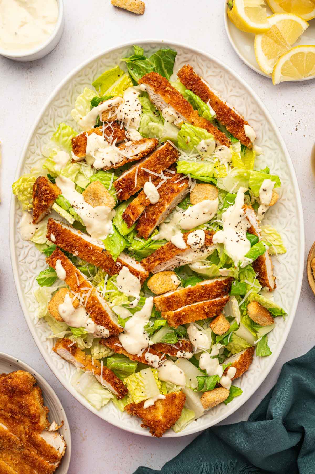 Crispy Chicken caesar salad served over a oval platter and garnished with grated parmesan cheese.