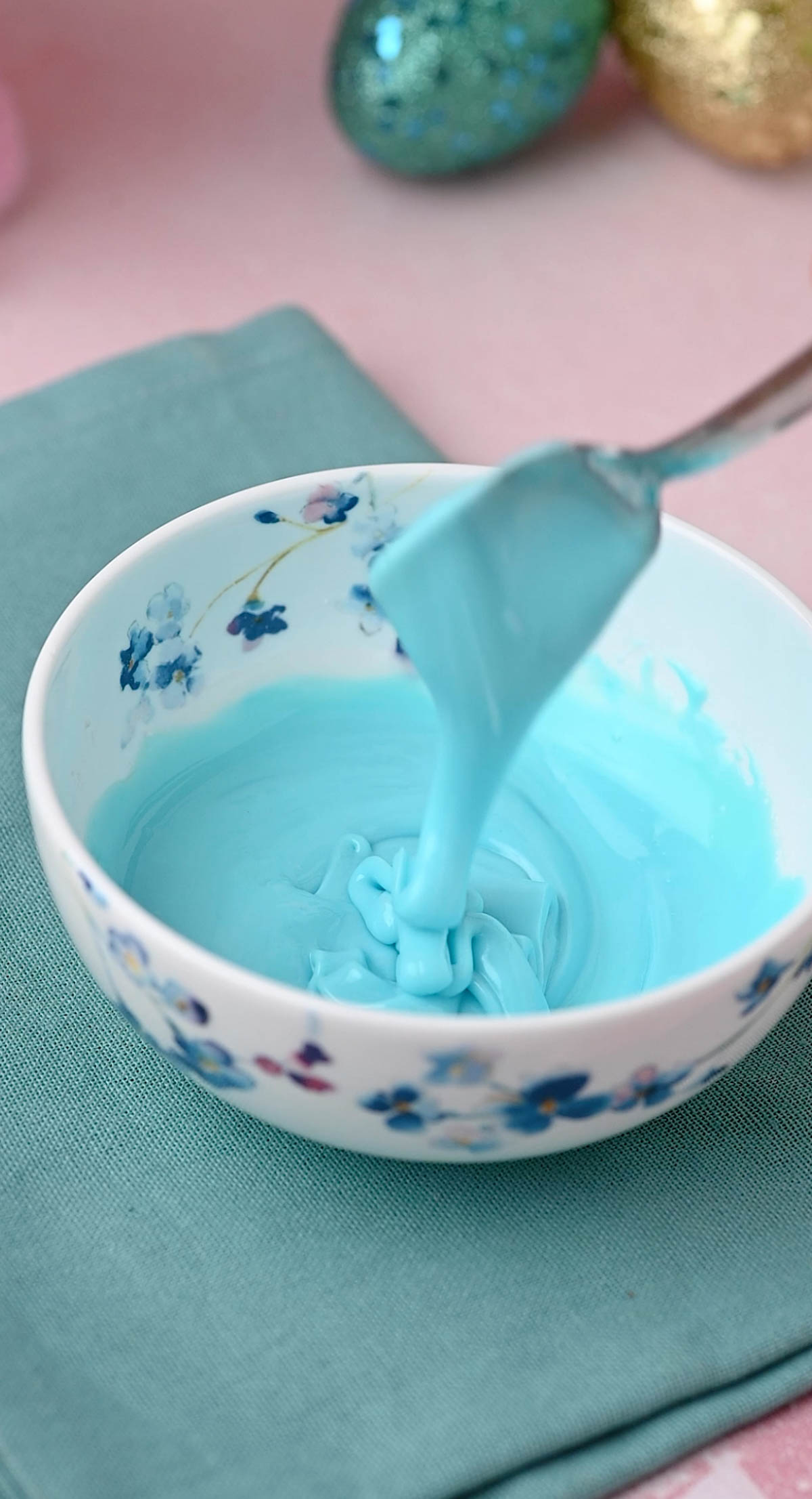 The spoon being mixed into the bowl for making pastel glaze.