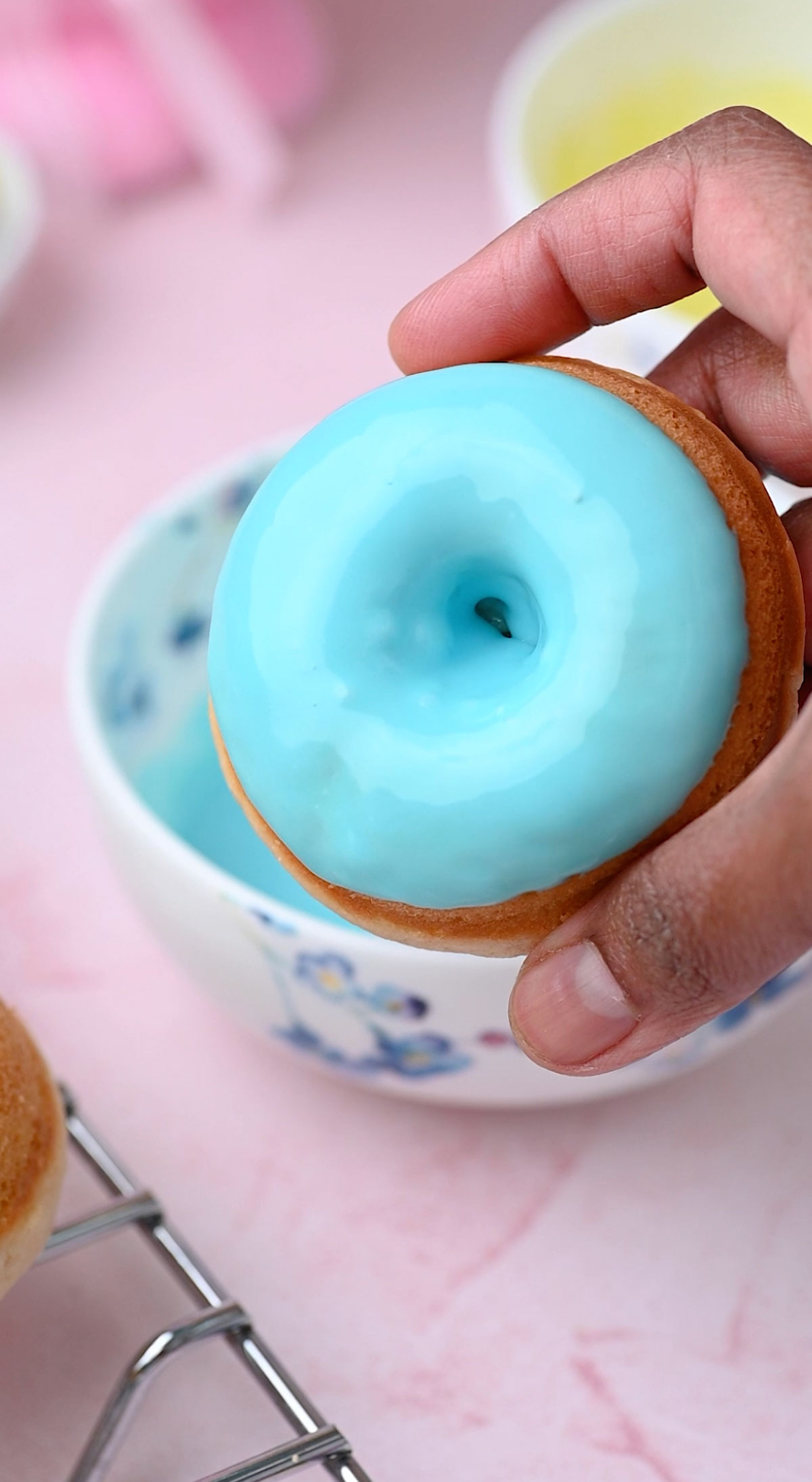 A hand showing pastel blue glazed donuts.