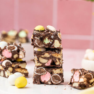 Easter Rocky Road stacked one above the other with easter decorations around on a pink background.