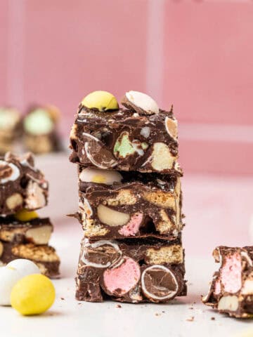 Easter Rocky Road stacked one above the other with easter decorations around on a pink background.