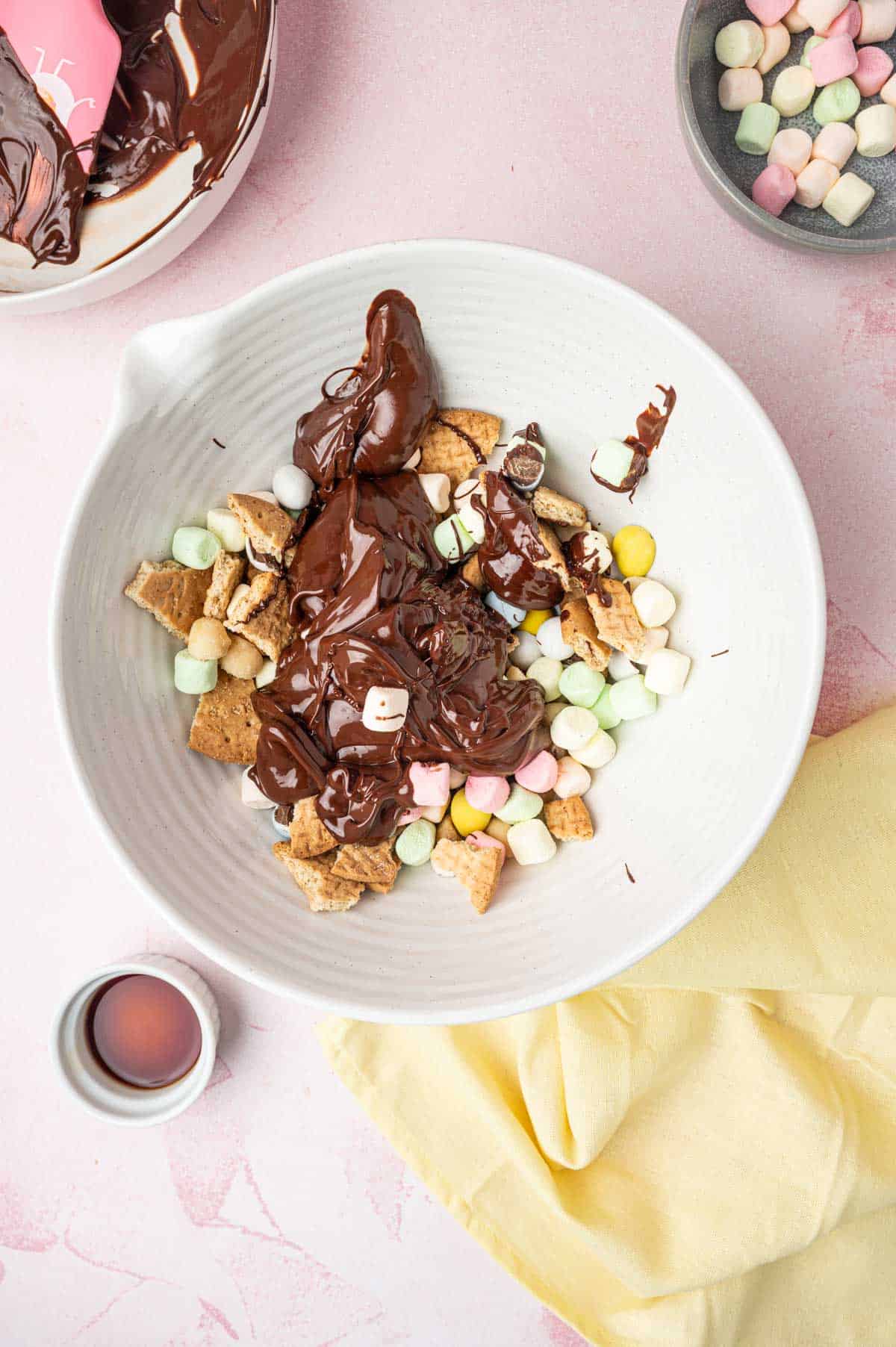 Melted chocolate added over the Easter chocolate addins in a white bowl for Easter Rocky road recipe.