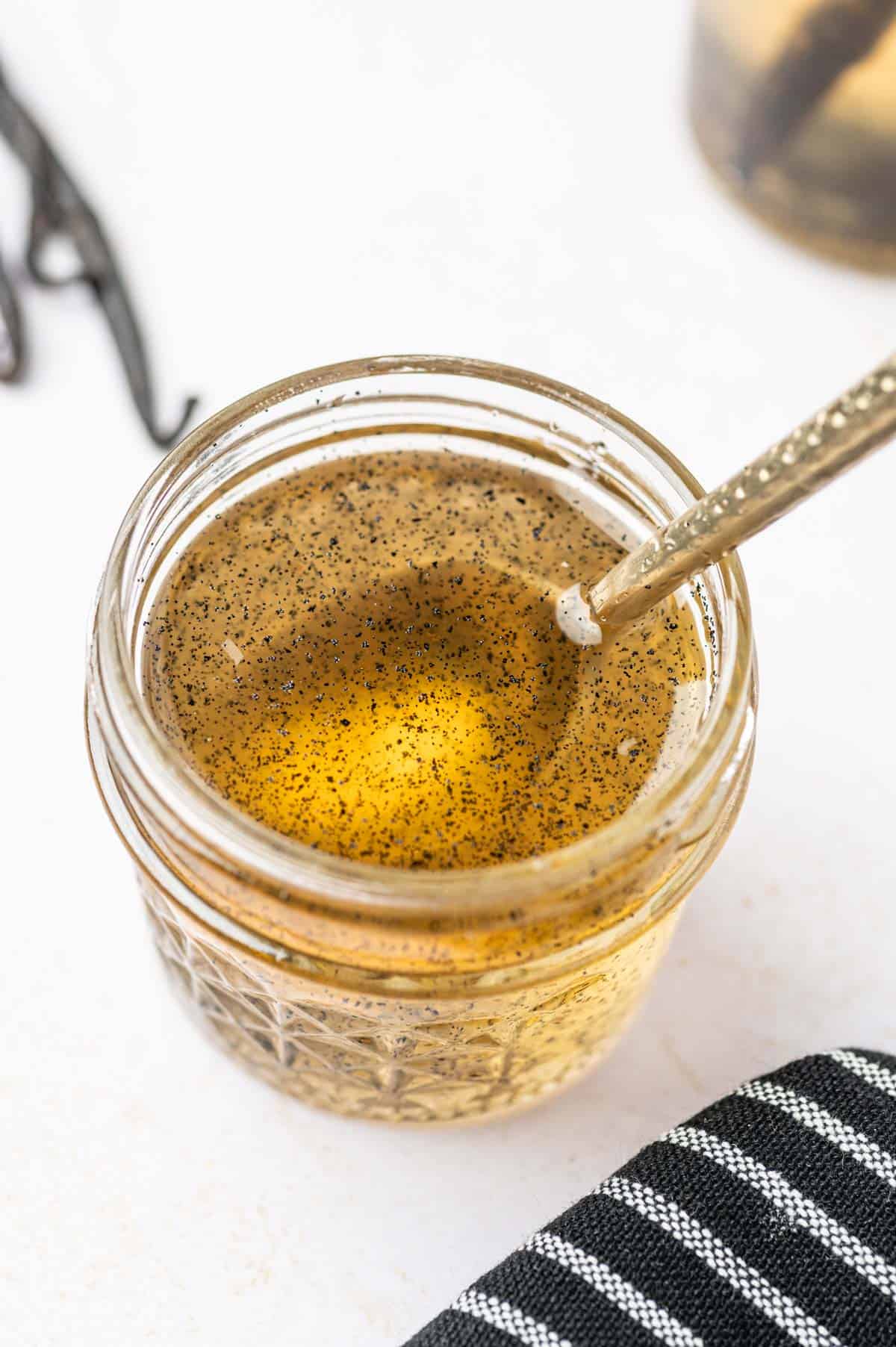 Vanilla bean coffee syrup in a glass jar with spoon on it.