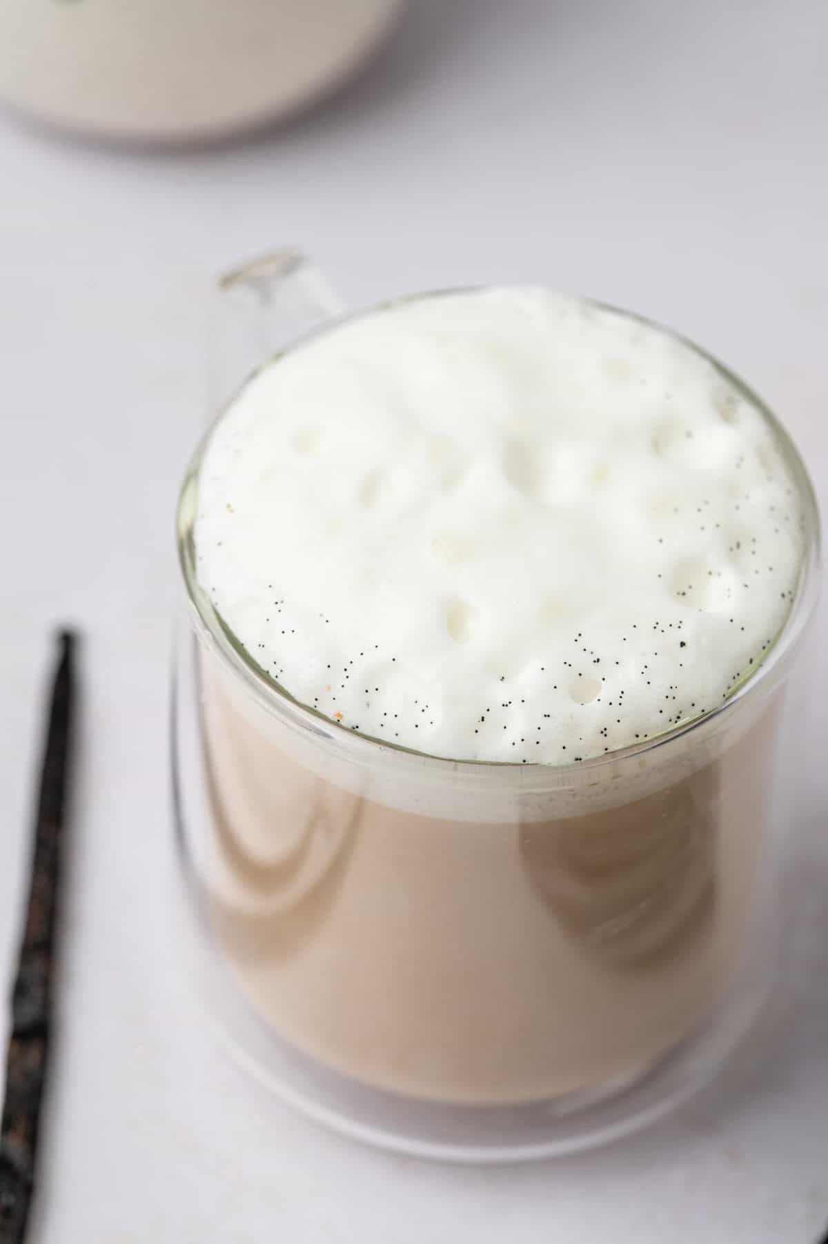 The close shot of vanilla bean latte in a clear glass mug.