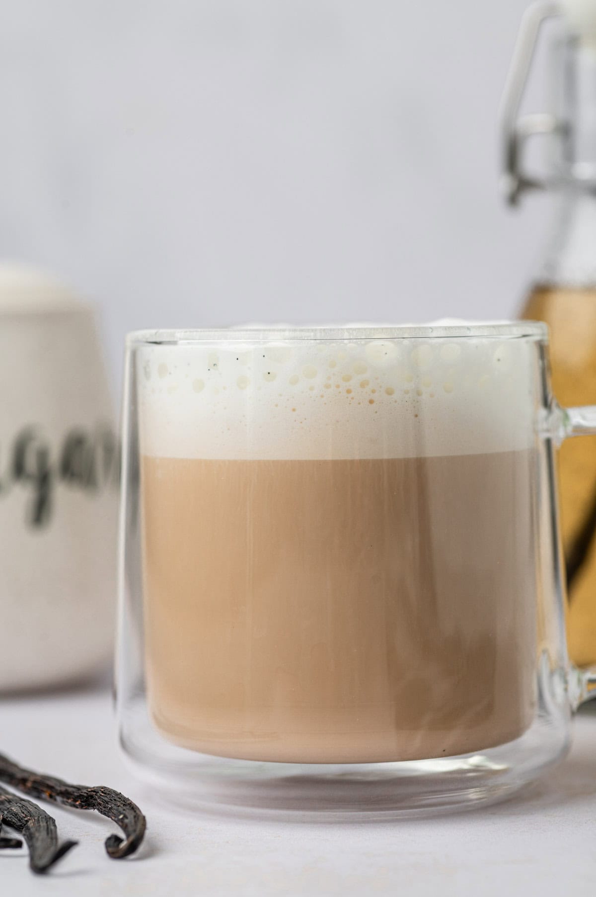 Homemade vanilla bean latte in a glass mug, vanilla bean in the side.