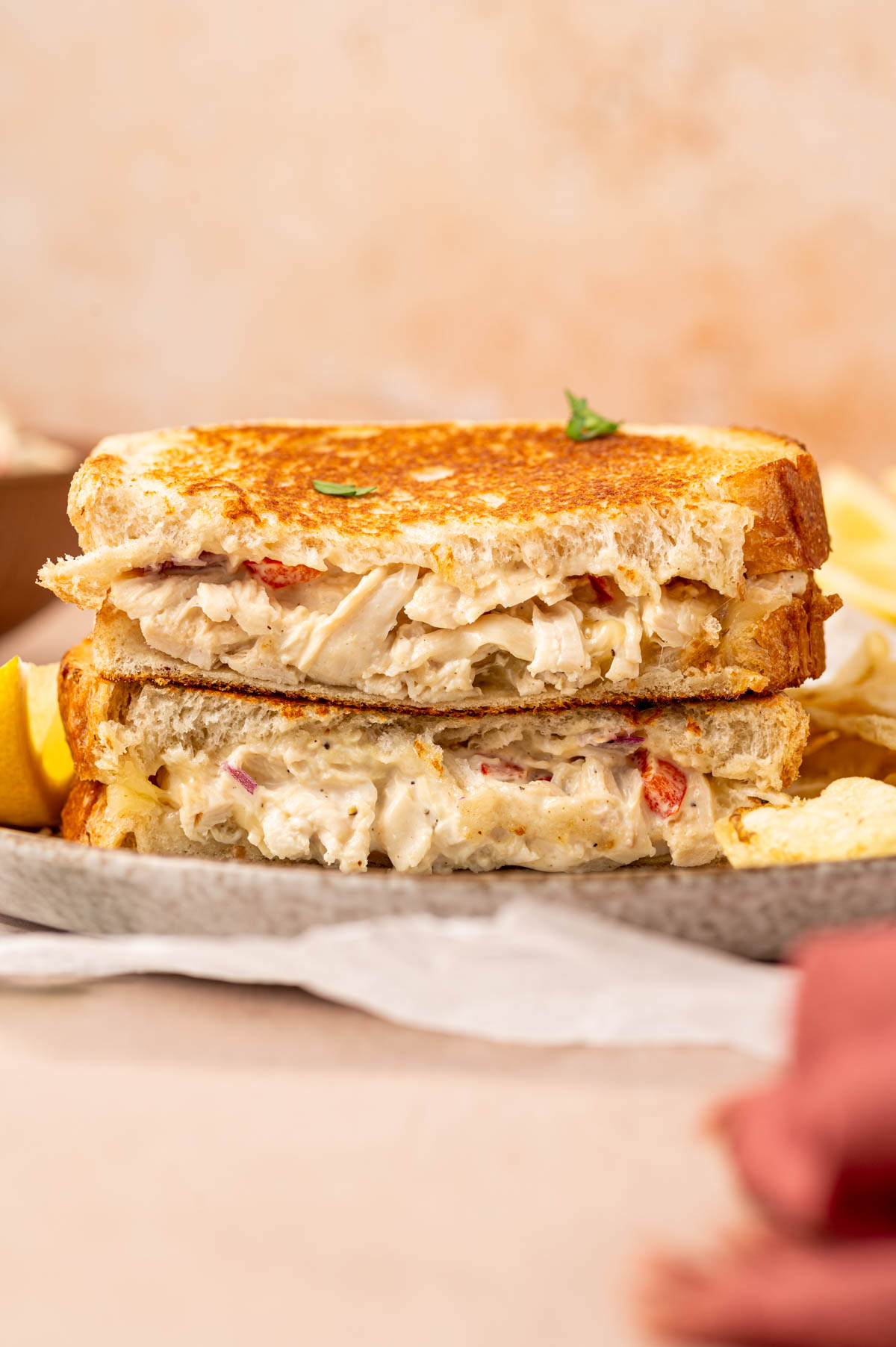 Golden-brown chicken salad melt sandwich, cut horizontally , with melted cheese and creamy chicken salad peeking out, served on a plate.