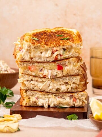 Close-up of a crispy chicken salad melt sandwich with golden toasted bread, melted cheese, and creamy chicken salad filling stacked one above the other.