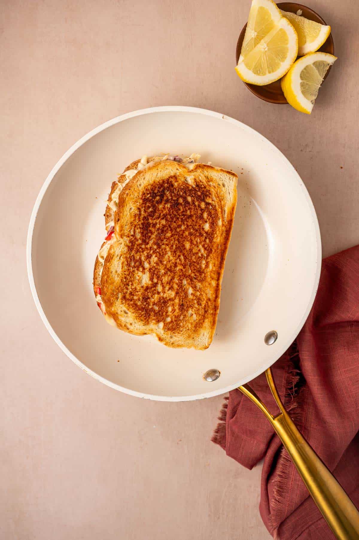 A perfectly grilled chicken salad melt sandwich on a frying pan.