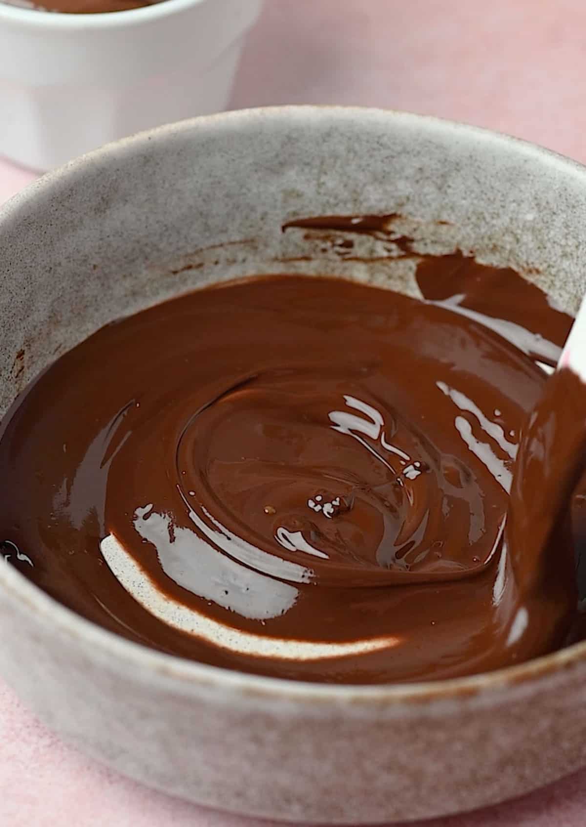 Melted dark chocolate in a bowl for nutella mousse recipe.