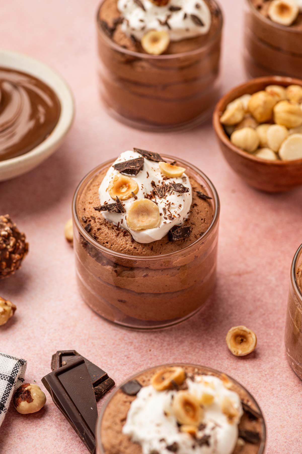 Elegant Nutella mousse in a clear glass topped with whipped cream, chocolate shavings, and chopped hazelnuts.
