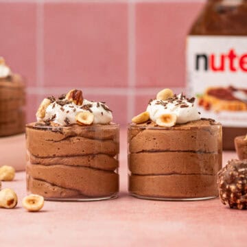 Nutella mousse piped into fancy serving cups, garnished with whipped cream and chocolate curls for a luxurious look.